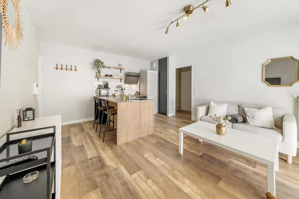 un salon avec un canapé blanc et une cuisine dans l'établissement VAUBAN - Appartement au calme - Parking/Terrasse, à Rennes