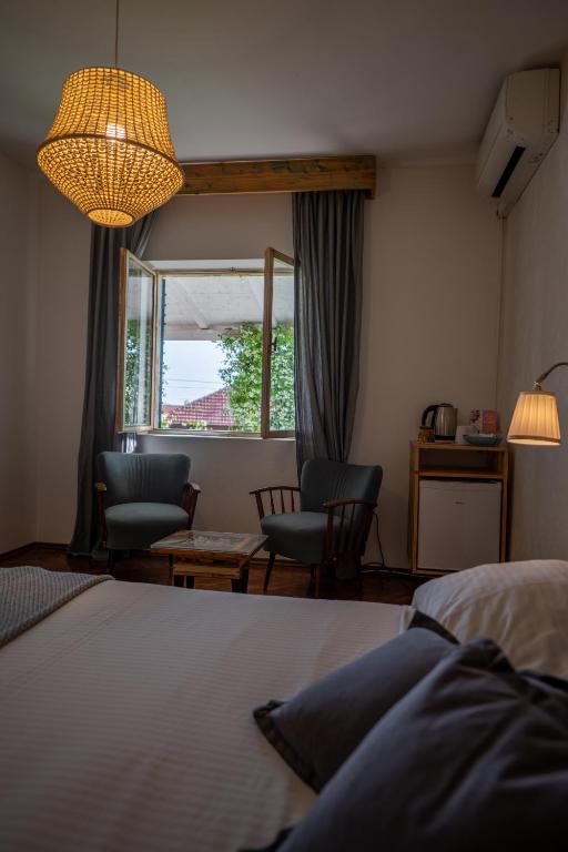 a bedroom with a bed and chairs and a window at Guest house Mediterranea in Pakoštane
