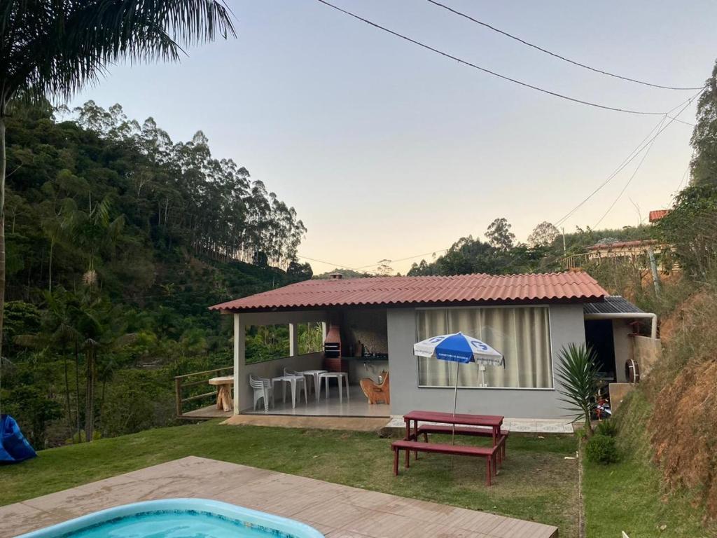 a small house with a picnic table and an umbrella at Recanto do Ziu in Santa Teresa