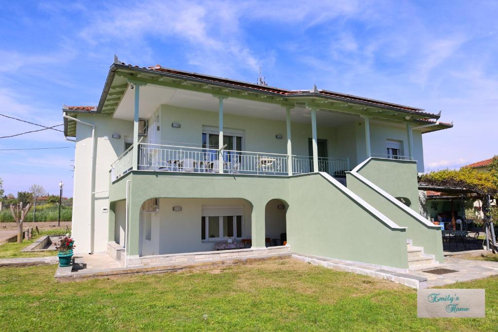 a white house with a balcony and a yard at Emily's Home in Epanomi