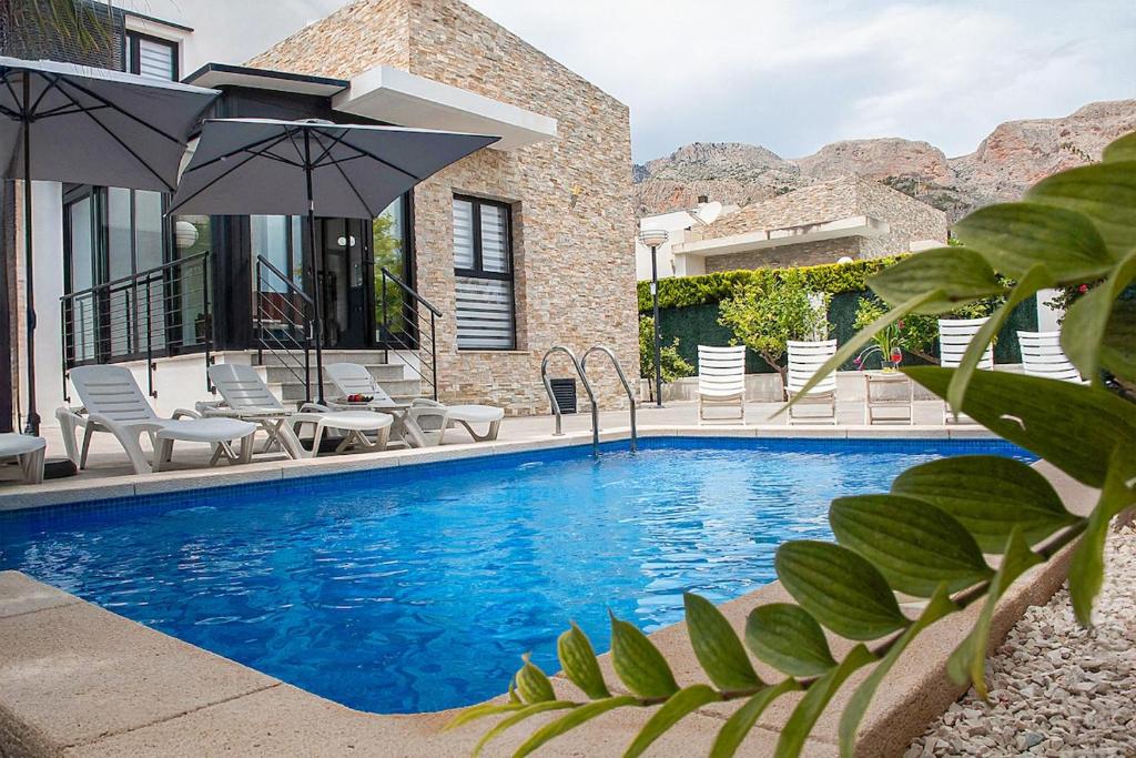 ポロップにあるModern villa with a private poolの家の隣にある椅子とパラソルのあるプール