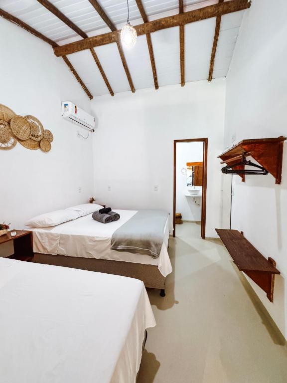 a bedroom with two beds and a bathroom at Pousada Flora Caraiva in Caraíva