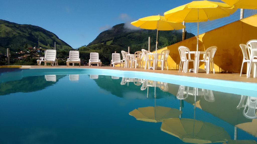un grupo de sillas y sombrillas junto a una piscina en Pousada Caminho de Minas, en Bocaina de Minas