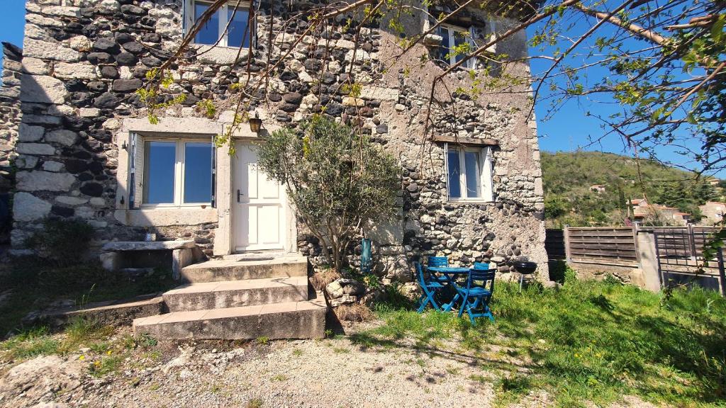 une maison en pierre avec une porte blanche et une chaise bleue dans l'établissement La Chambonnière, à Chomérac