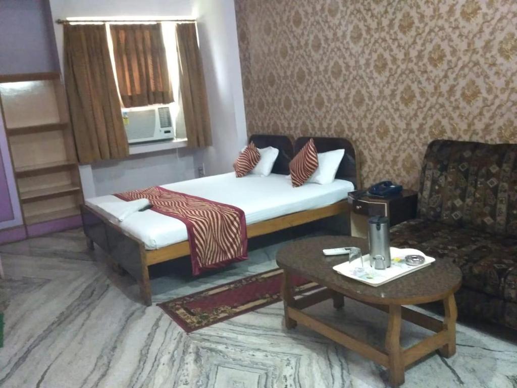 a room with a bed and a couch and a table at Hotel Utsav Delux in Patna