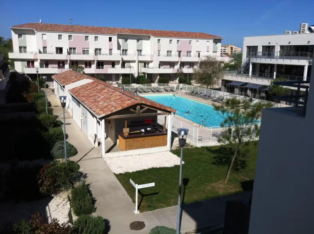 an overhead view of a building and a swimming pool at LE BLEU CAMARGUE - T3 EN DUPLEX CLASSÉ 3 ETOILES - CLIM - ARRIVÉE AUTONOME - Piscine privative à la résidence - Parking Gratuit - Wifi FIBRE - Animaux acceptés - Idéale Famille couple télétravail in Le Grau-du-Roi