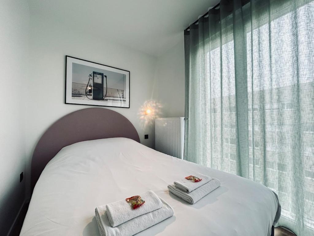 une chambre avec un lit blanc avec des serviettes dessus dans l'établissement 602 Studio équipé à 2 pas du centre ville et gare, à Reims