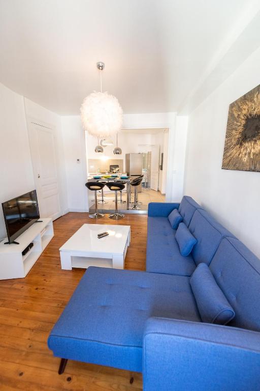 un salon avec un canapé bleu et une table dans l'établissement KASA ZAMBEZE - Spacious - Equipped - Wi-Fi, à Saint-Étienne