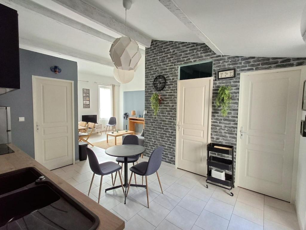 - un salon avec une table et des chaises ainsi qu'un mur en briques dans l'établissement Air-conditioned 2-room balcony apartment for 4 people - La Ciotat, à La Ciotat