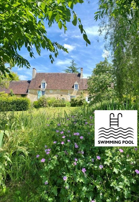 une maison avec un panneau devant un champ de fleurs dans l'établissement La Breteche du Perche, à Saint-Germain-de-la-Coudre