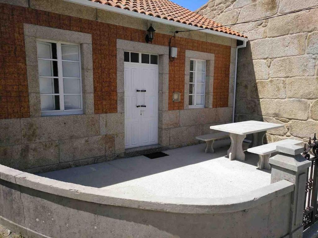 a patio with two benches and a white door at Casa da Miniña in Quilmas