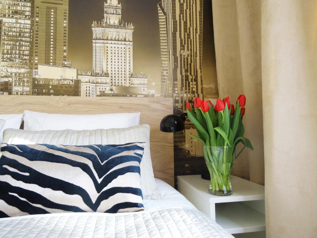 a bedroom with a vase of red tulips on a bed at Studio Plac Bankowy in Warsaw