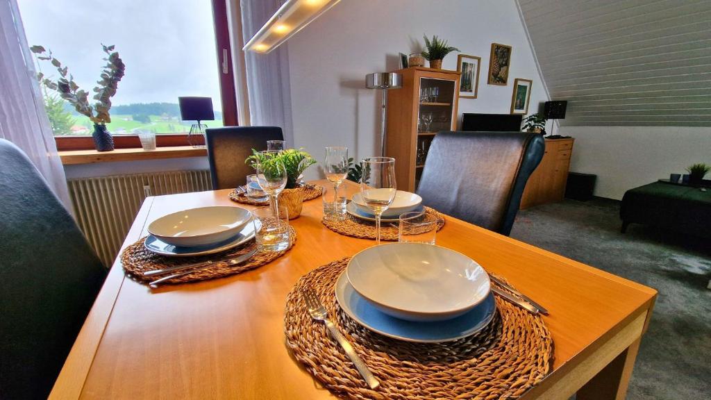 einem Holztisch mit Tellern und Geschirr darauf in der Unterkunft Urlaub mit Talblick in Schönwald im Schwarzwald in Schönwald