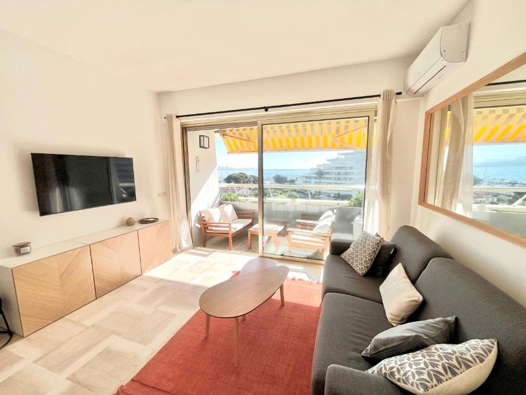 un salon avec un canapé et une télévision dans l'établissement Marina Baie studio vue mer et jardin avec clim, à Villeneuve-Loubet