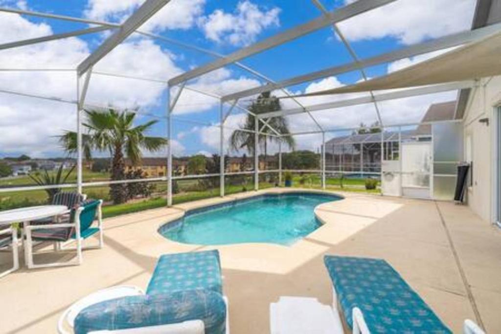 a swimming pool with blue chairs and a patio at Unique comfortable Golf course Home w Private Pool in Davenport