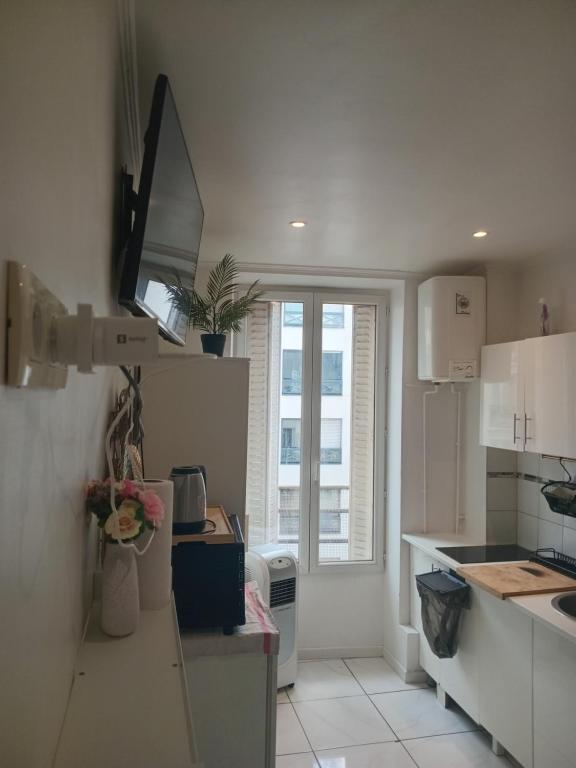 Il comprend une cuisine avec des placards blancs et une télévision murale. dans l'établissement Chambre proche centre ville, à Paris