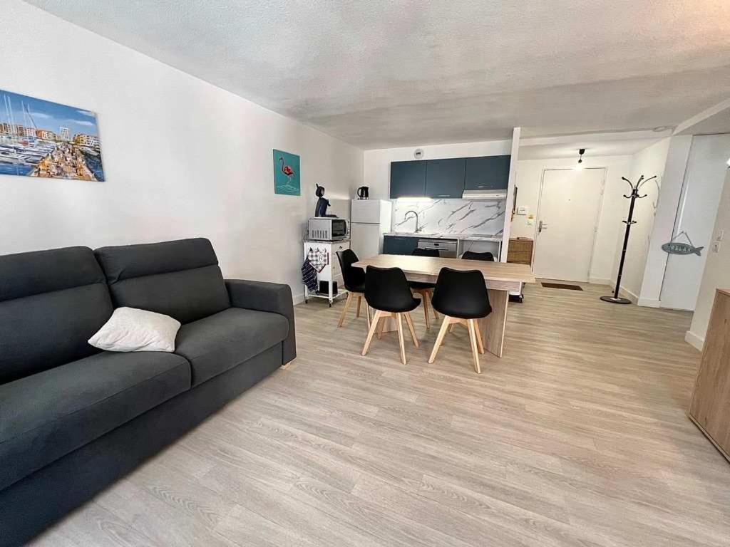 un salon avec un canapé, une table et des chaises dans l'établissement Agde-Loc Appartement des Flaneries, au Cap d'Agde