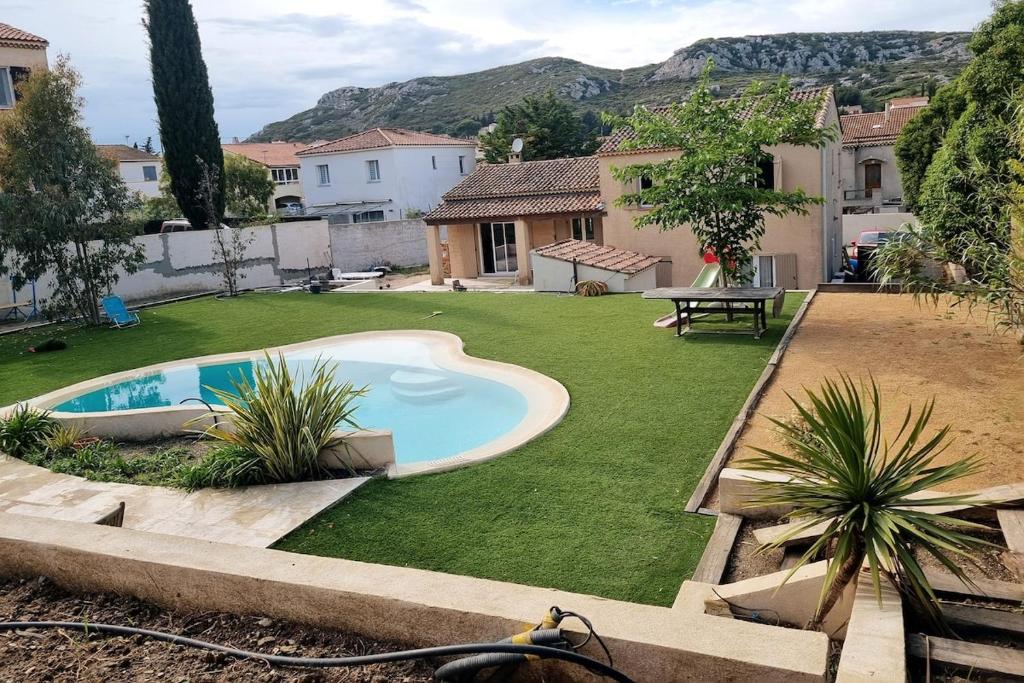 une cour avec une piscine et une pelouse dans l'établissement Maison avec piscine, proche calanques et mer, à Le Rove