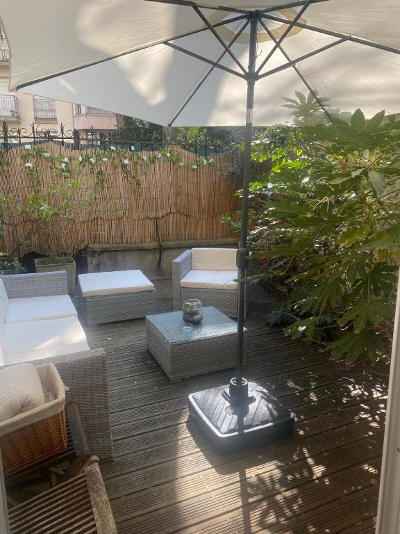 une terrasse avec un parasol, des canapés et des chaises dans l'établissement Maison à Paris, à La Celle-sous-Gouzon