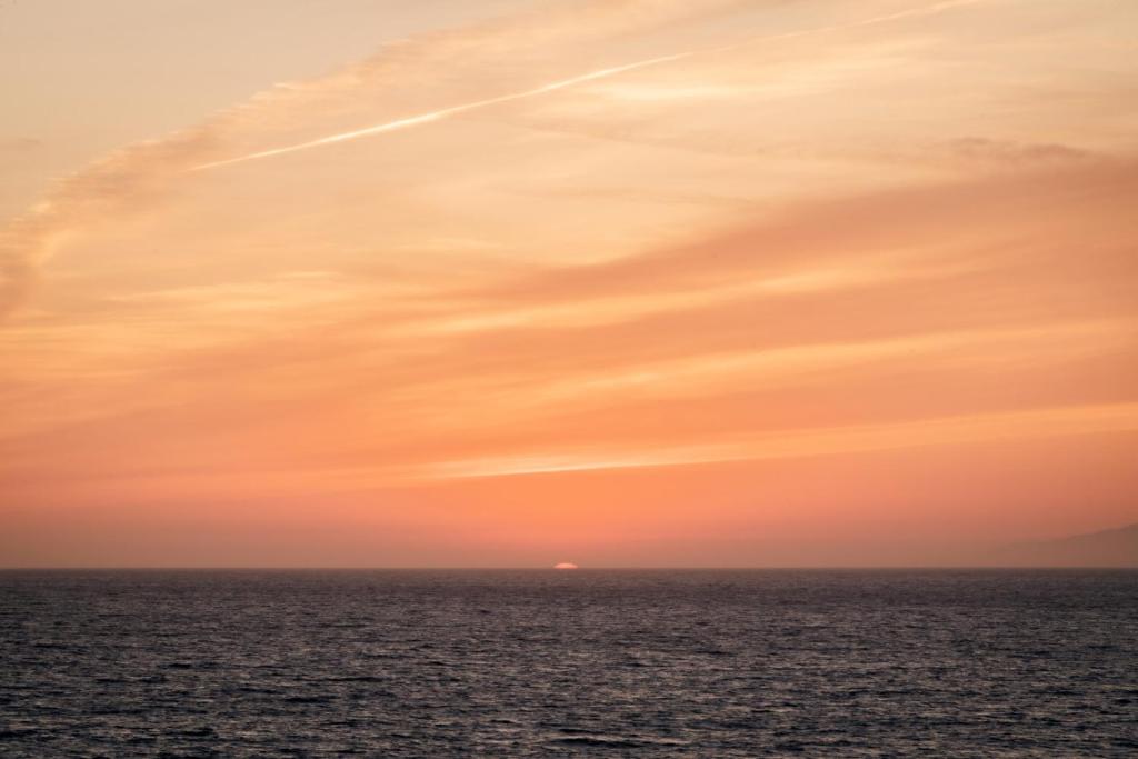 Un cielo naranja sobre el océano al atardecer en New Listing The Nautilus Manhattan Beachfront Retreat, en Manhattan Beach