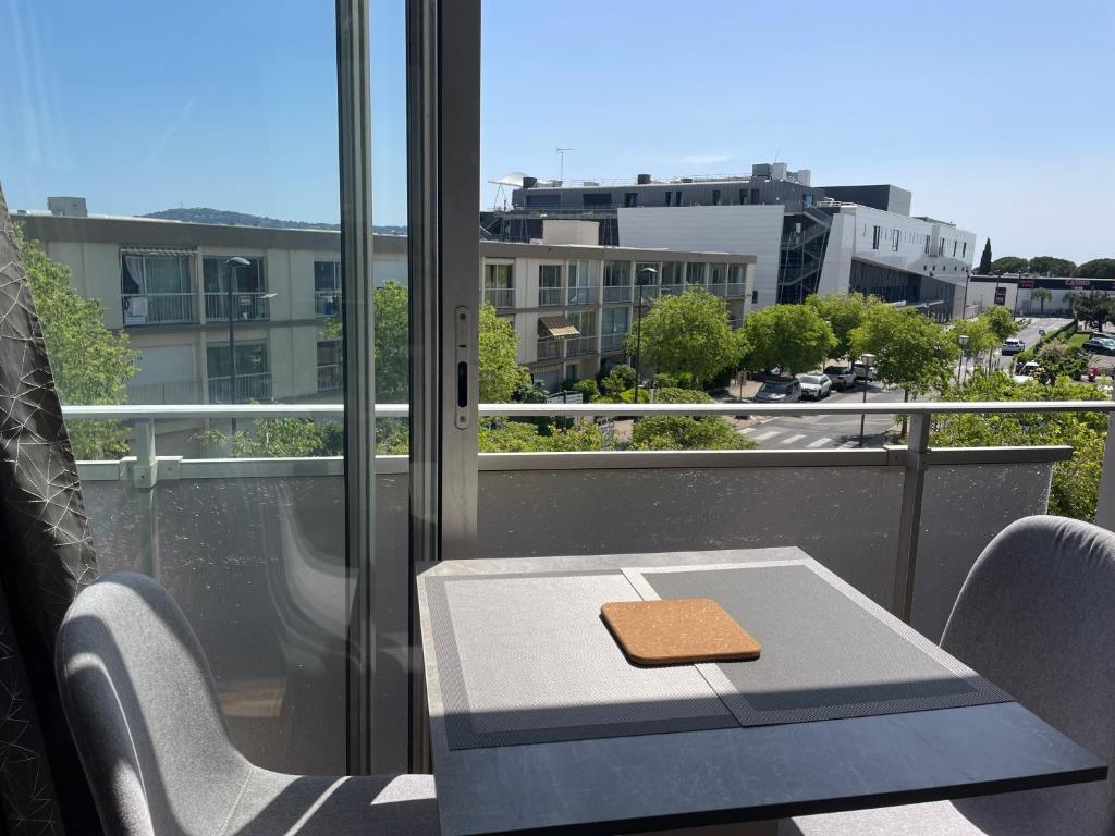 une table et des chaises sur un balcon avec vue sur une ville dans l'établissement T1 bis rénové et cosy à côté des Thermes et de l'étang de Thau, à Balaruc-les-Bains