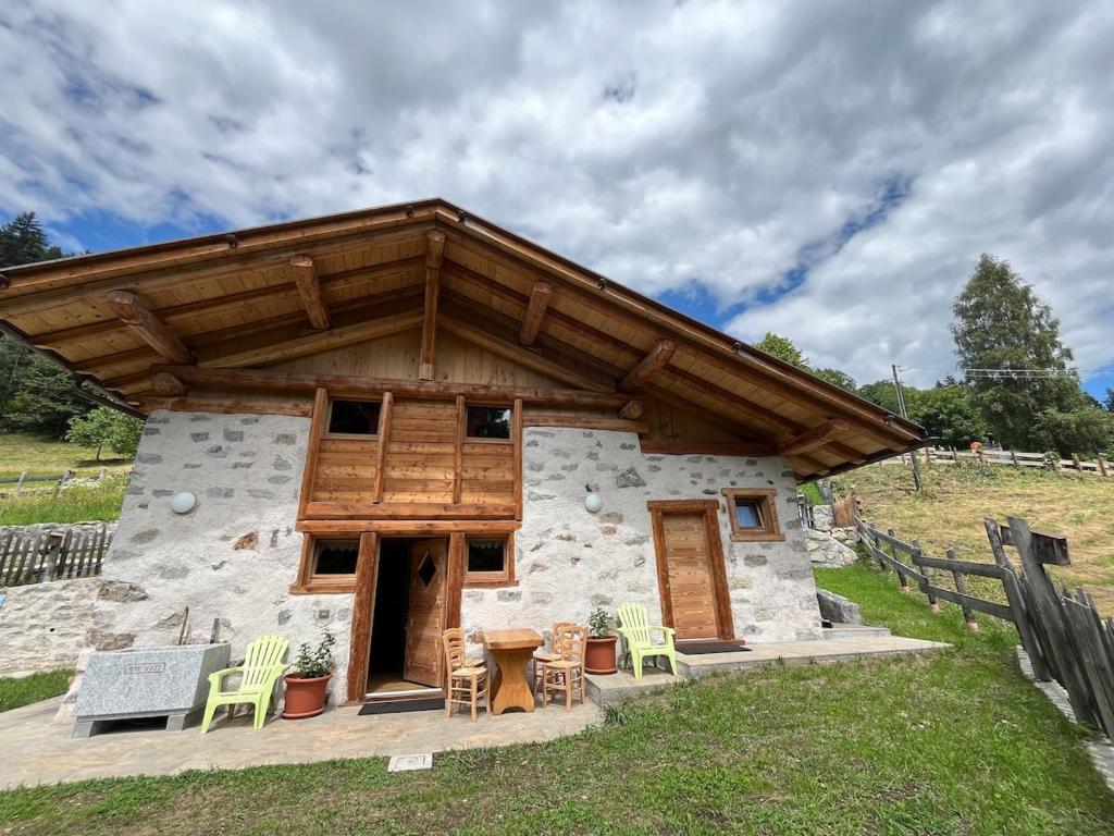 a log cabin with a wooden roof and a table and chairs at Mountain Chalet in Strembo