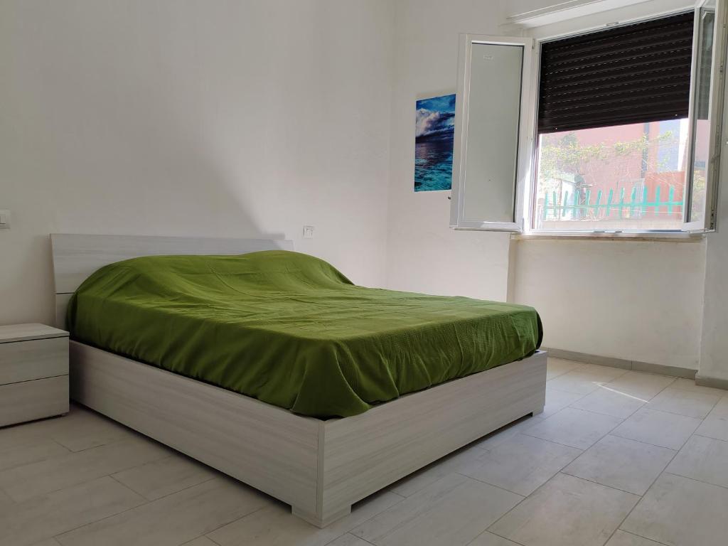 een slaapkamer met een bed met een groene deken erop bij Villettina con Bagni esclusivi in Collesalvetti