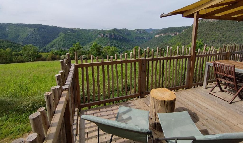a wooden deck with chairs and a table and a fence at Tiny Mirador à la Ferme in Tréves