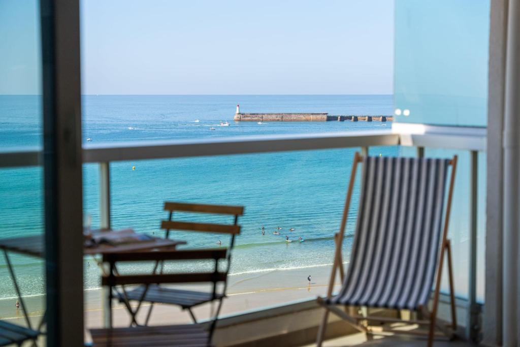 deux chaises et une table sur un balcon avec l'océan dans l'établissement Appartement coup de cœur face à l’océan, à Les Sables-dʼOlonne