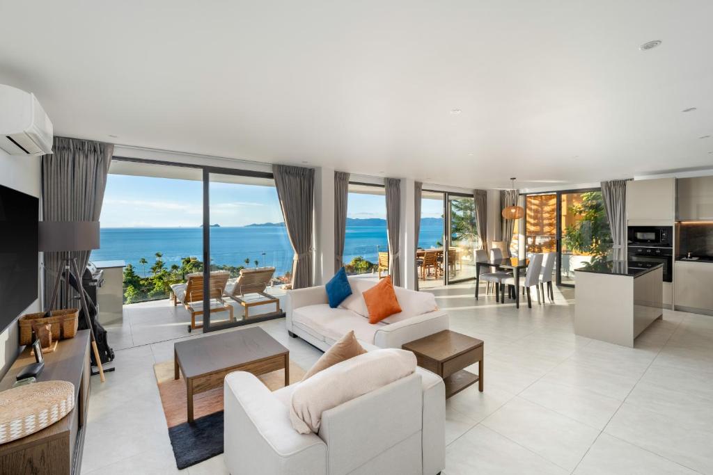 Una sala de estar con muebles blancos y vista al mar. en Reve Samui Luxe Seafront Residence with Panoramic Views, en Ban Bang Po
