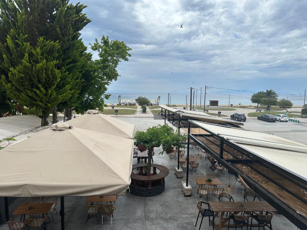 an outdoor patio with tables and umbrellas and chairs at Tropical apartment in Flogita