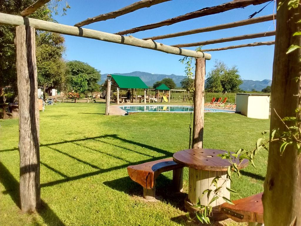 un banco de madera en un patio con piscina en La Posada De Juan en Coronel Moldes