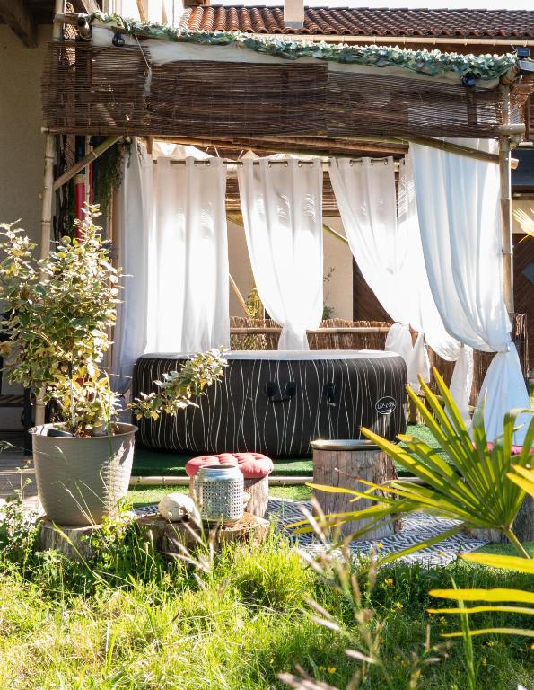 a patio with white curtains and plants in a yard at Les gardiens de la vallée in Figeac