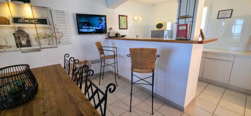 eine Küche mit einem Tisch und eine Bar mit Hockern in der Unterkunft Gîte Palma, vue exceptionnelle vallée Provençale in Le Barroux
