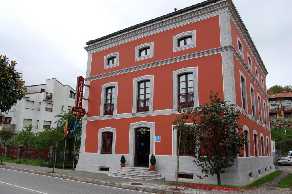 a red building on the corner of a street at Puente Romano in Cangas de Onís