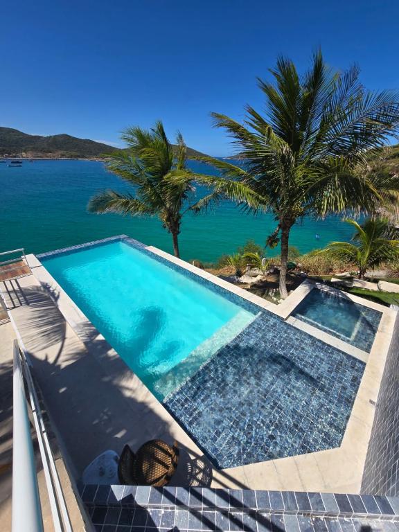 a swimming pool with a view of the ocean at Pousada Atalaia Boutique FR in Arraial do Cabo