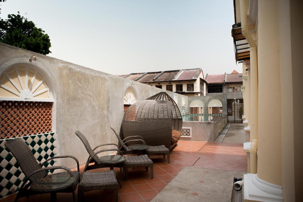 a patio with chairs and a bird cage on a wall at Jawi Peranakan Mansion in George Town