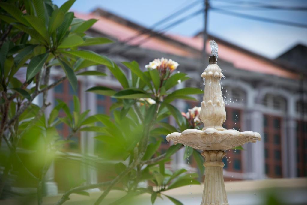 a white statue in front of some plants at Jawi Peranakan Mansion in George Town