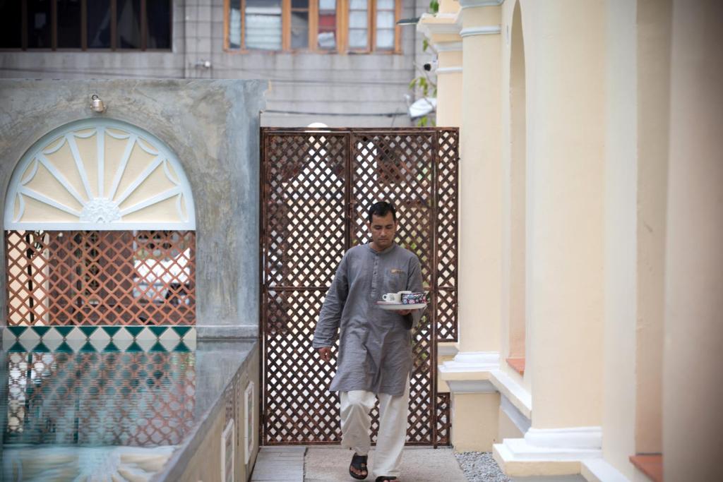 a man walking into a building with a box in his hand at Jawi Peranakan Mansion in George Town