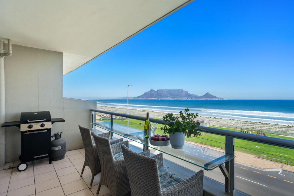 a balcony with a table and chairs and a view of the beach at Sea Spray B306 in Bloubergstrand