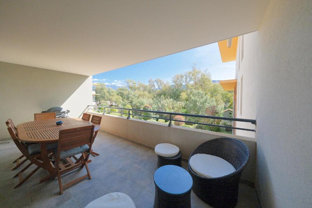 a balcony with a table and stools and a view at Magnifique T3 proche de la plage in Calvi