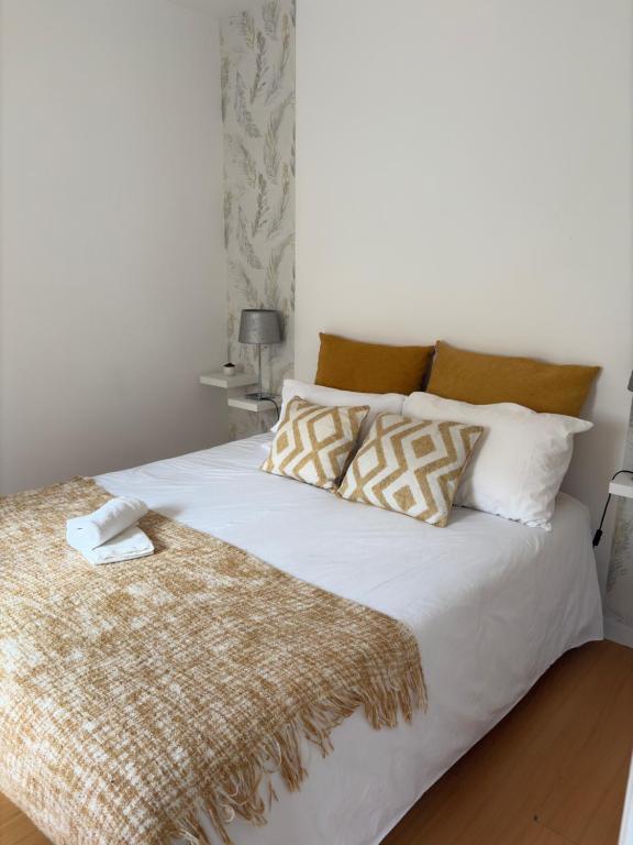 a white bed with a brown blanket and pillows at City Break-Quiet House with Private Patio in Torres Vedras