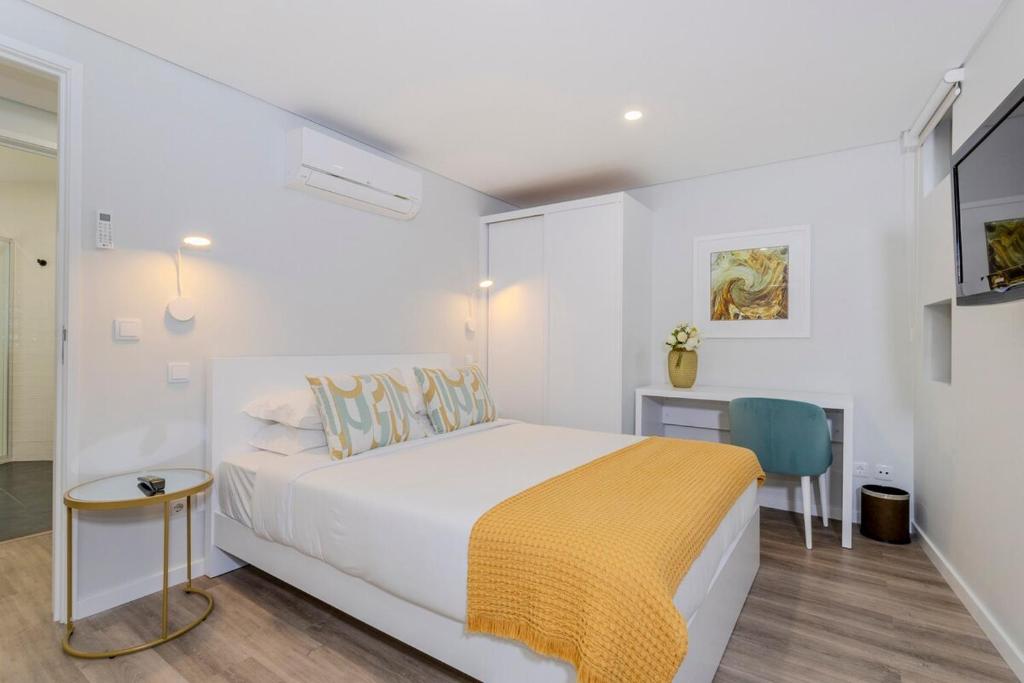 Un dormitorio blanco con una cama y un escritorio. en GuestReady - Casa do Senhor do Colégio, en Ponta Delgada