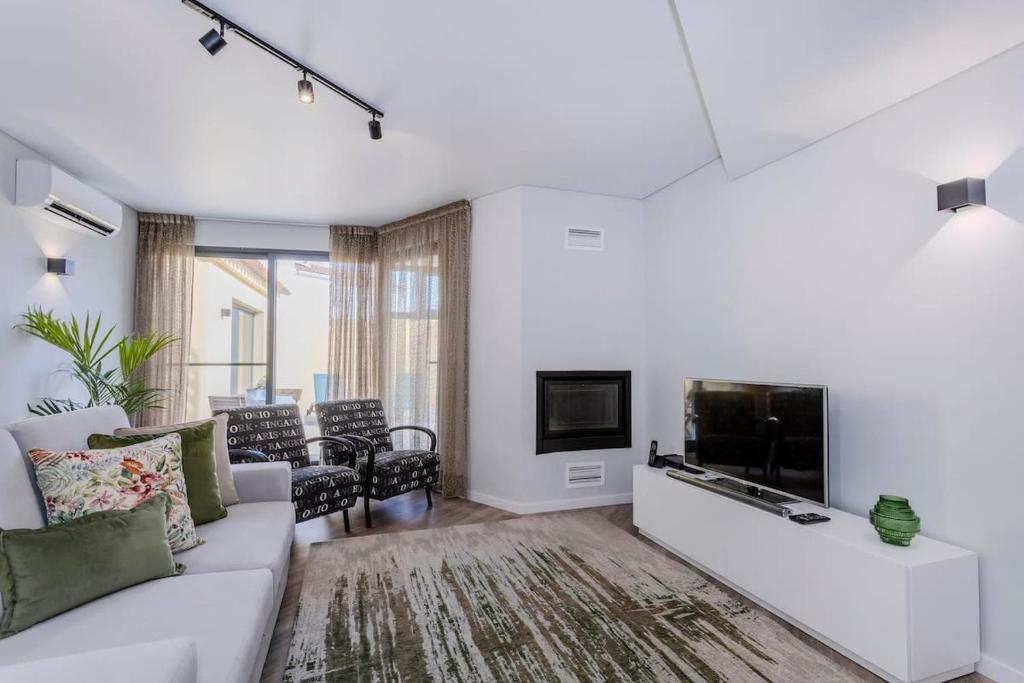 a living room with a white couch and a tv at Casa do Senhor do Colégio in Ponta Delgada