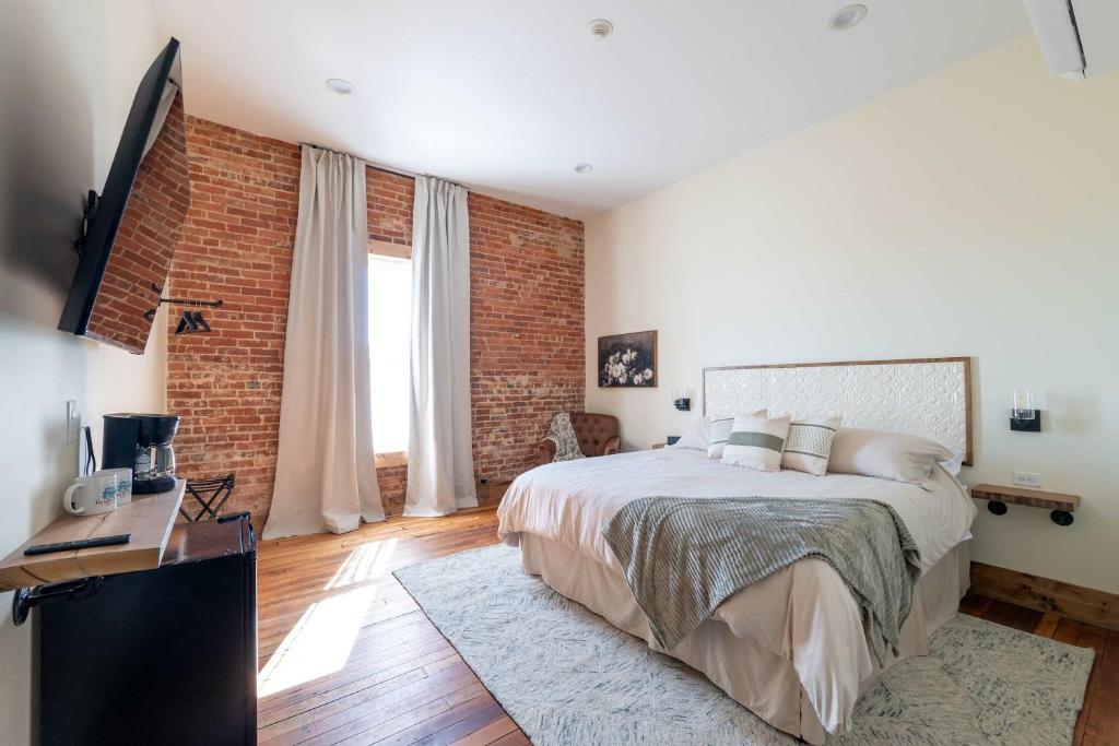 Un dormitorio con una cama y una pared de ladrillo. en Courtyard King - Room 4, en Versailles