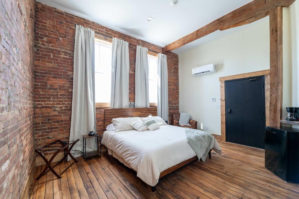 Un dormitorio con una cama y una pared de ladrillo. en ADA Suite - Room 6, en Versailles