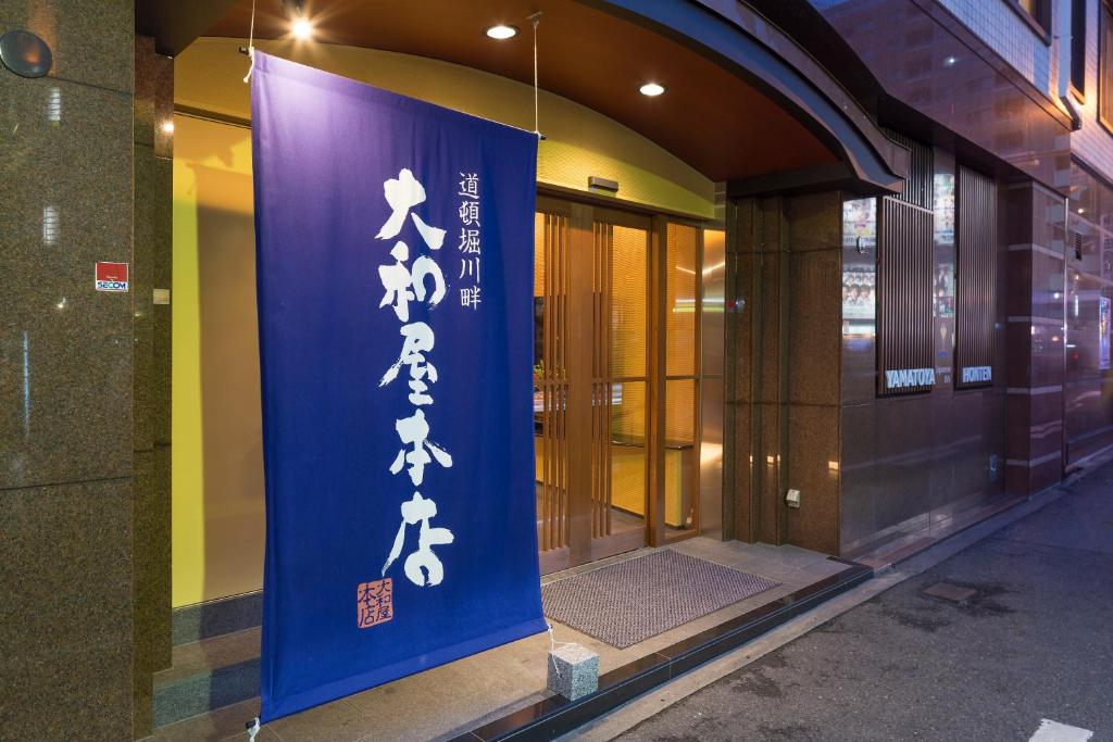 a sign on the side of a building at Yamatoya Honten Ryokan Osaka in Osaka