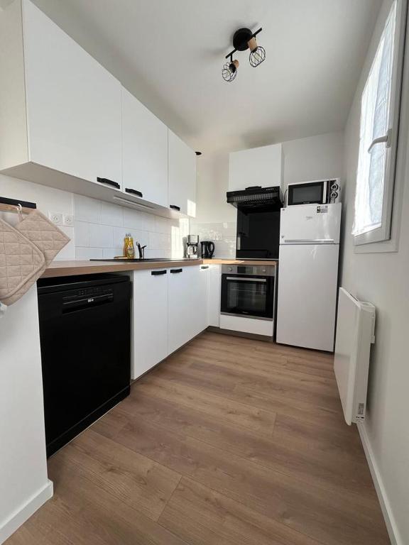 une cuisine avec des armoires blanches et des appareils noirs dans l'établissement Location maison Audierne, à Audierne