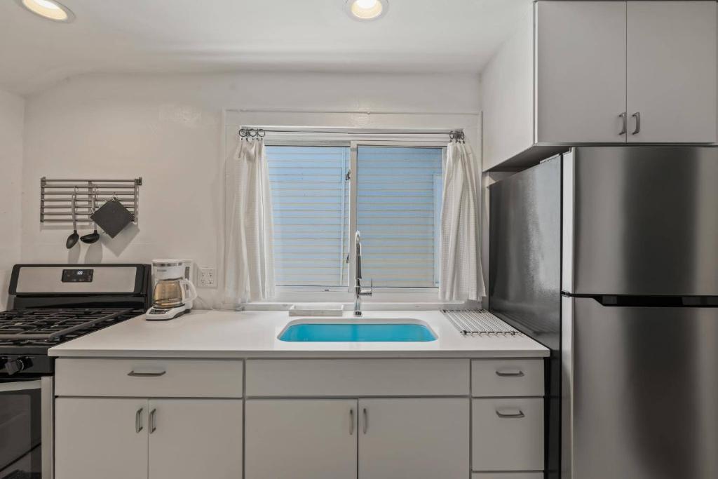a white kitchen with a sink and a refrigerator at Stylish Apt in Walker's Point in Milwaukee