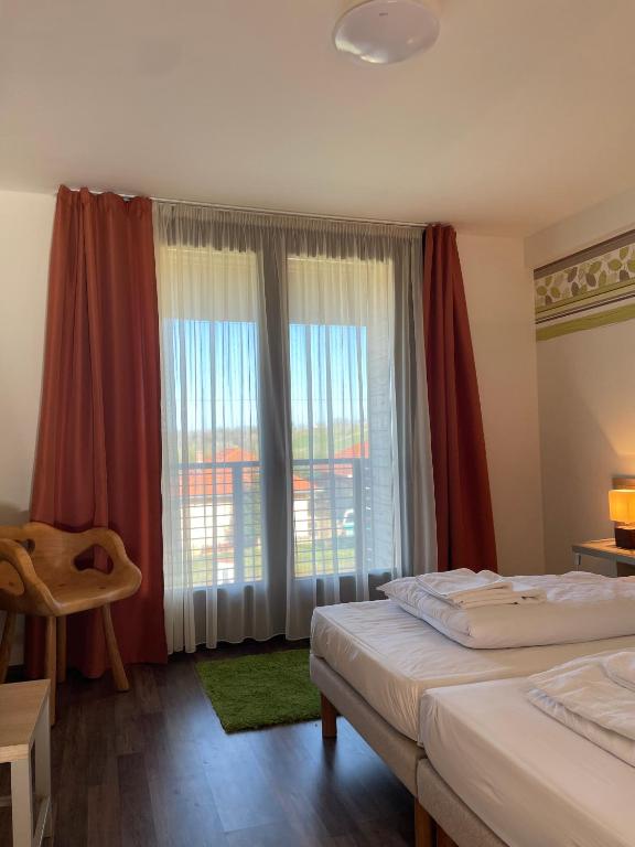 a bedroom with two beds and a large window at Kisfaludy Kásté in Dobronhegy